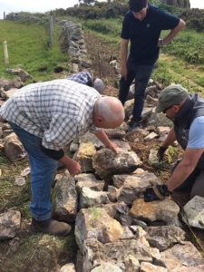 Three men building a stone wall