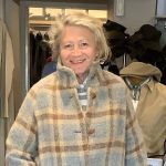 A smiling woman wearing a winter coat in a clothing store.