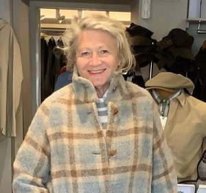 A smiling woman wearing a winter coat in a clothing store.