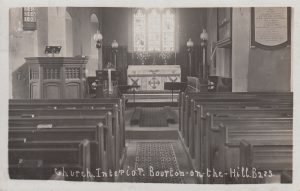Archive photograph labelled, 'Church Interior. Bourton on the Hill.' The picture inside St Lawrence Church looks down the aisle towards the altar, with wooden pews either side. The wooden pulpit stands to the left with the choir stalls behind. A stained glass window is above the altar.