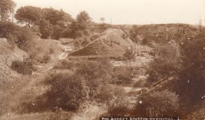 The picture is labelled 'The Quarry, Bourton on the Hill'. The sepia image show tracks around a slope with trees and hedges, indicating the quarry was probably no longer active by the time this photograph was taken.
