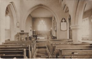 The interior of a church with an arched window behind the altar. Pews are in rows to the right and left.